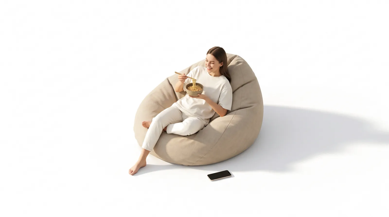 A woman relaxing on a beanbag eating a bowl of noodles, her phone on the floor beside her